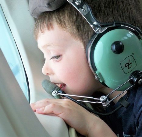 A young boy wearing headphones and sitting in an airplane.