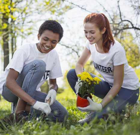 A man and woman kneeling in the grass holding flowers.