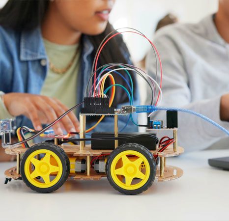 A couple of people sitting at a table with some small toy cars.